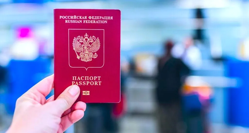 Счастливая туристка с паспортом и чемоданом в аэропорту